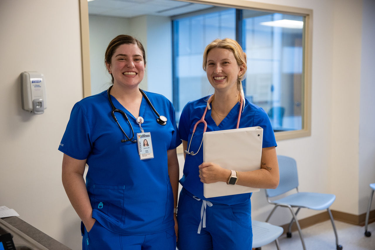 Two healthcare professionals in blue scrubs standing together